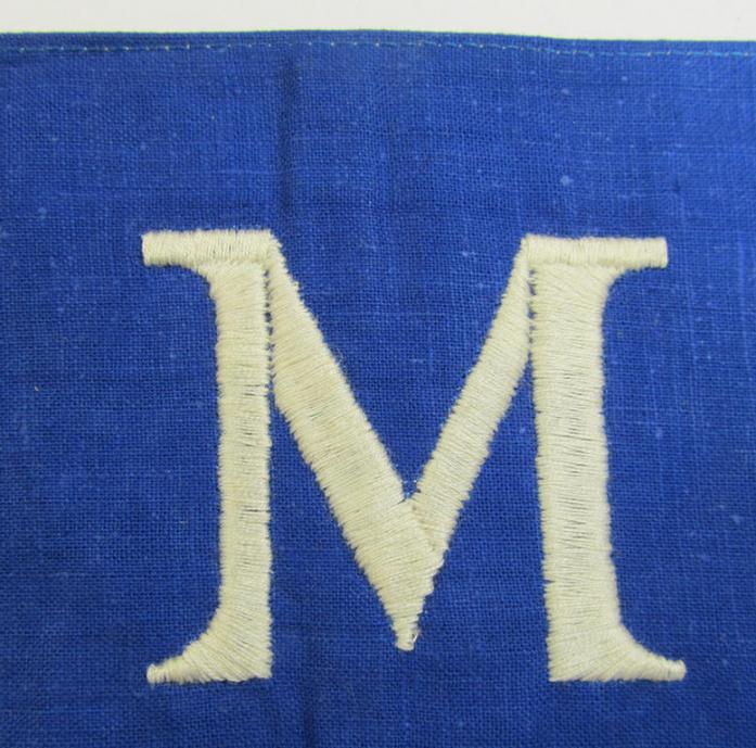Linnen-based- and/or partly machine-woven-, darker-blue-coloured armband (ie. 'Armbinde') depicting a capital 'M'-character, as was presumably intended for staff-members of the German RLB (ie. 'Reichsluftschutz-Bund')