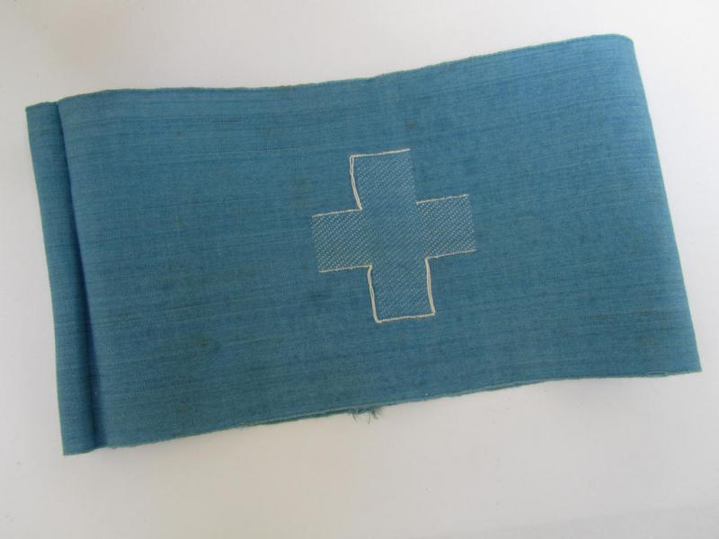 Light-blue-coloured so-called: RLB (or: 'Reichsluftschutzbund') 'Feldscher'- (ie. 'Sanitäter') armband depicting the typical white-coloured cross and showing an interwoven size-(unit-?) designation (that reads: '7')