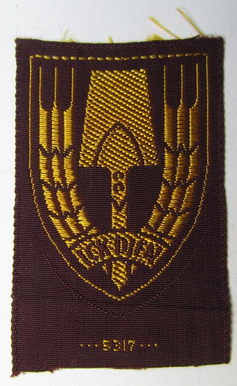 Neat - and nicely 'BeVo-woven'-like - Dutch WWII-period, labour service ie. 'Nederlandse Arbeidsdienst' (or: NAD) cap-badge entitled: 'Ick Dien' and that comes in a 'virtually mint- ie. unissued', condition