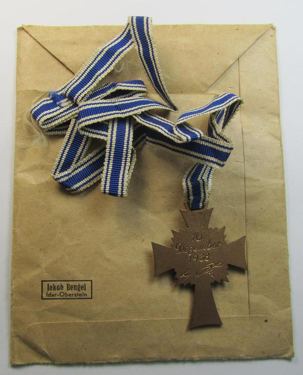 Attractive, 'Ehrenkreuz der deutschen Mutter - dritte Stufe' (or: bronze-class mothers'-cross) that came mounted onto its long-sized ribbon and that came stored in its period pouch (by the maker: 'Jakob Bengel - Idar-Oberstein')