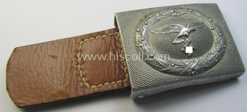 Attractive, WH (Luftwaffe) silver-coloured and aluminium-based belt-buckle, being a maker- (ie. 'F.W. Assmann & Söhne'-) marked example that comes mounted onto its leather-based tab and that comes in a minimally used condition