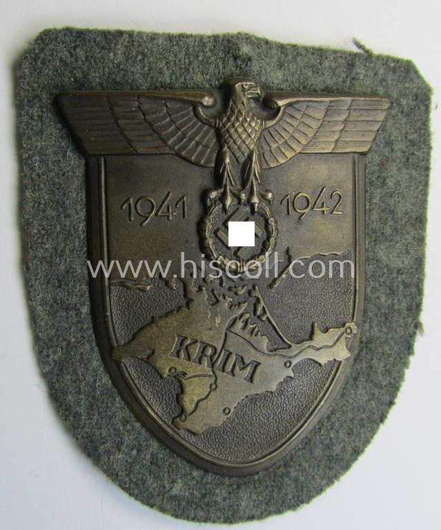 Attractive, WH (Heeres o. Waffen-SS) 'Krim'-campaign-shield that comes mounted onto its original, field-grey-coloured 'backing' and that comes in a surely issued-, minimally worn and/or (I deem) carefully tunic-removed-, condition