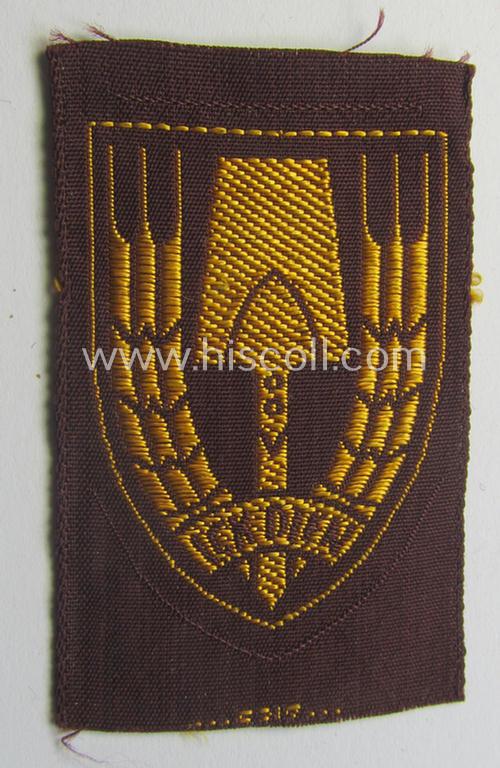 Neat - and nicely 'BeVo-woven'-like - Dutch WWII-period, labour service ie. 'Nederlandse Arbeidsdienst' (or: NAD) cap-badge entitled: 'Ick Dien' and that comes in a 'virtually mint- ie. unissued', condition