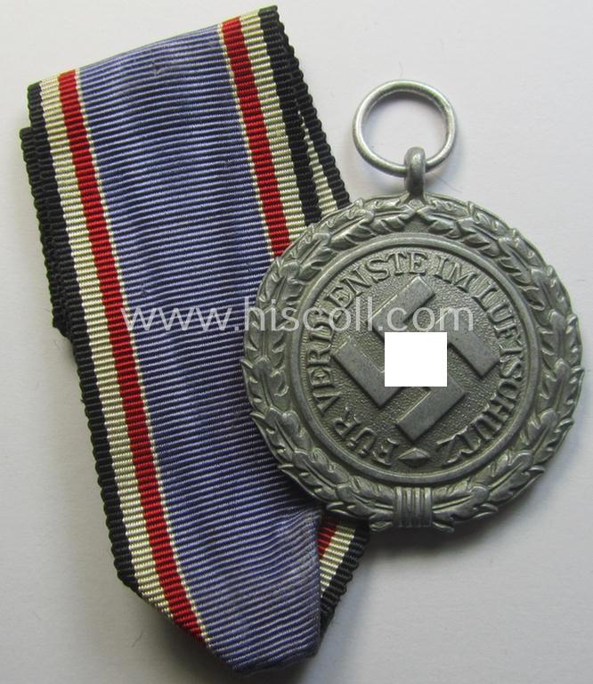 'Luftschutz-Ehrenzeichen 2. Stufe' being a maker- (ie. '10'-) marked example, as executed in (heavy) zinc-based metal (ie. 'Feinzink') and that came together with its period ribbon (ie. 'Bandabschnitt')