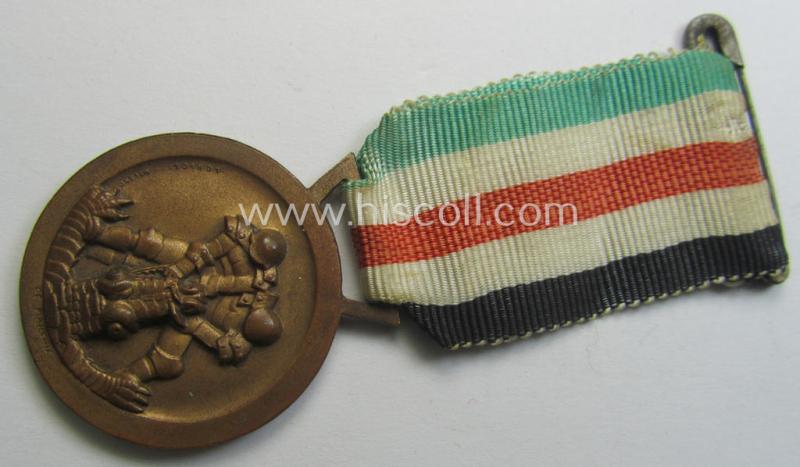 Golden-bronze-coloured- (and I deem 'Buntmetall'-based-) example of a: 'Deutsch-Italienische Feldzugsmedaille' (or: German-Italian campaign-medal) that comes mounted onto its (regular-sized) piece of original (and minimally faded!) ribbon