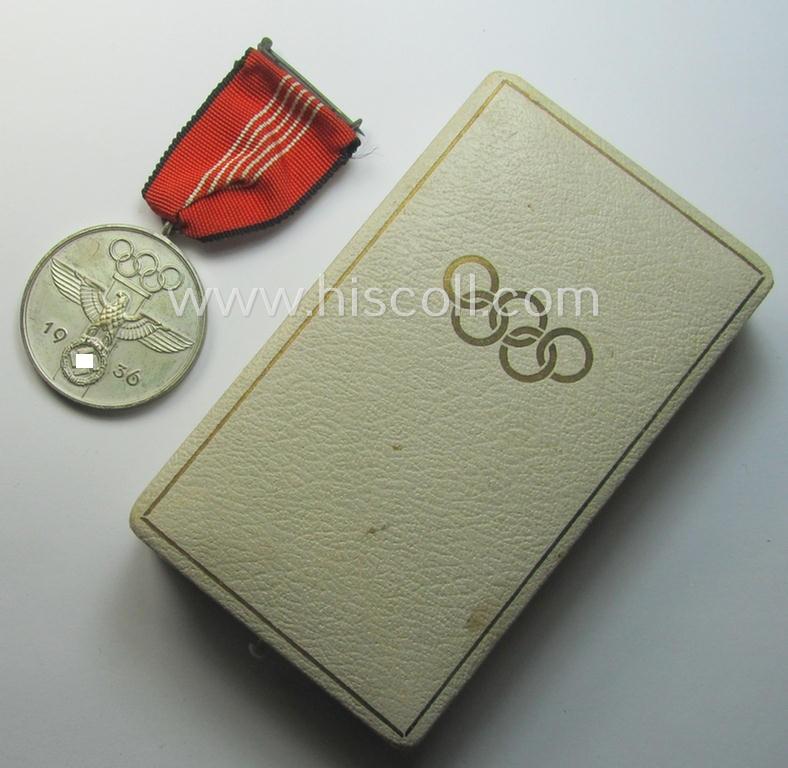 'Deutsche Olympia-Erinnerungsmedaille 1936' being a non-maker-marked example that comes mounted onto its original ribbon (ie. 'Bandabschnitt') and that comes stored in its typical, beige-white-coloured etui