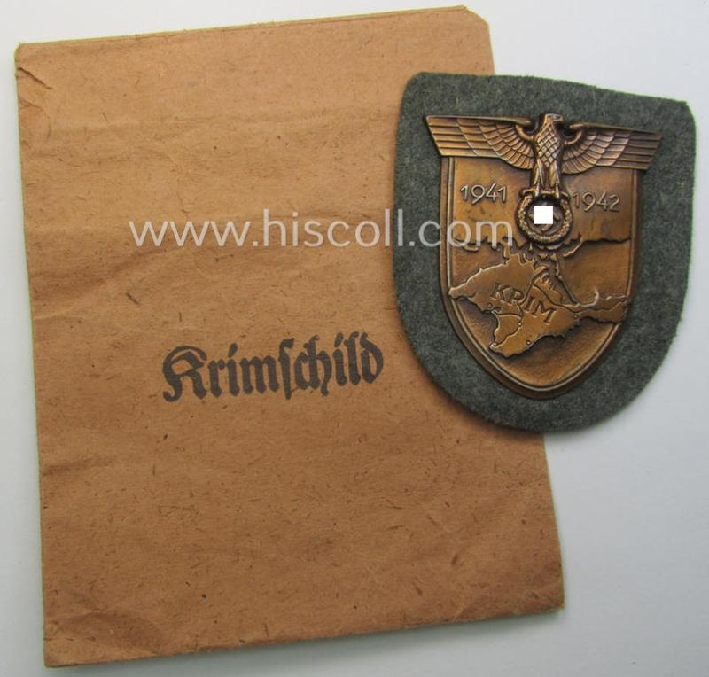 WH (Heeres ie. Waffen-SS) 'Krim'-campaign-shield (by the maker: 'Friedrich Orth') that comes stored in its period (and rarely seen!) 'Zellstoff'-based pouch and that comes in a probably issued- (albeit still 'virtually mint'-), condition