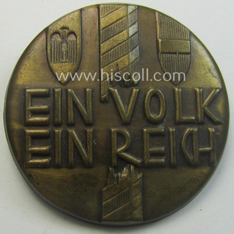 Golden-bronze-toned, N.S.D.A.P.-related day-badge (ie. 'tinnie' or: 'Veranstaltungsabzeichen') showing a broken border-pole, three provincial shields and that is entitled: 'Ein Volk - Ein Reich'