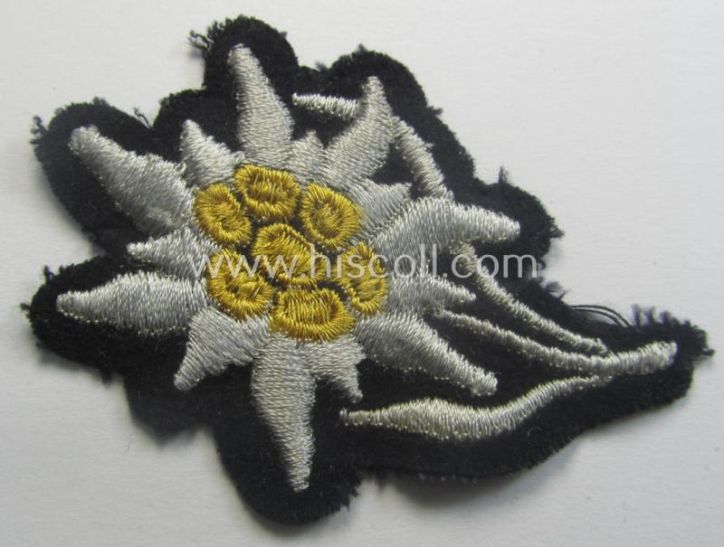 Waffen-SS-pattern, black-coloured M43-cap-insignia (ie. 'Mützenabzeichen') depicting an: 'Edelweiss'-flower as used by the various 'Gebirgsjäger'- (ie. mountain-troops-) related divisional-staff