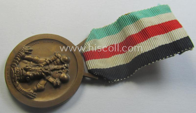 Golden-bronze-coloured- (and I deem 'Buntmetall'-based-) example of a: 'Deutsch-Italienische Feldzugsmedaille' (or: German-Italian campaign-medal) that comes mounted onto its (regular-sized) piece of original (and minimally faded- ie. stained!) ribbon