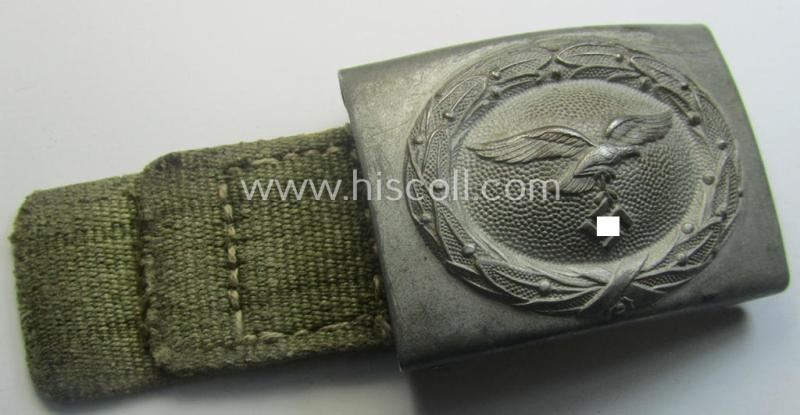 WH (Luftwaffe) 'tropical-issued' belt-buckle being a non-maker-marked, greyish-silver-coloured example that comes mounted onto its original, greenish-coloured- (and/or: 'webbing'-based-) tab
