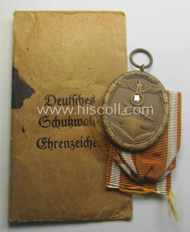 Medal-set: 'Deutsches Schutzwall Ehrenzeichen' (aka: 'Westwall'-medal) being a non-maker-marked- and/or: typical 'Buntmetall'-based specimen that comes packed in its original pouch of issue by the: 'Deschler & Sohn'-company