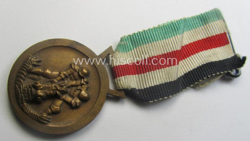 Golden-bronze-coloured- (and I deem 'Buntmetall'-based-) example of a: 'Deutsch-Italienische Feldzugsmedaille' (or: German-Italian campaign-medal) that comes mounted onto its (regular-sized) piece of original (and minimally faded!) ribbon