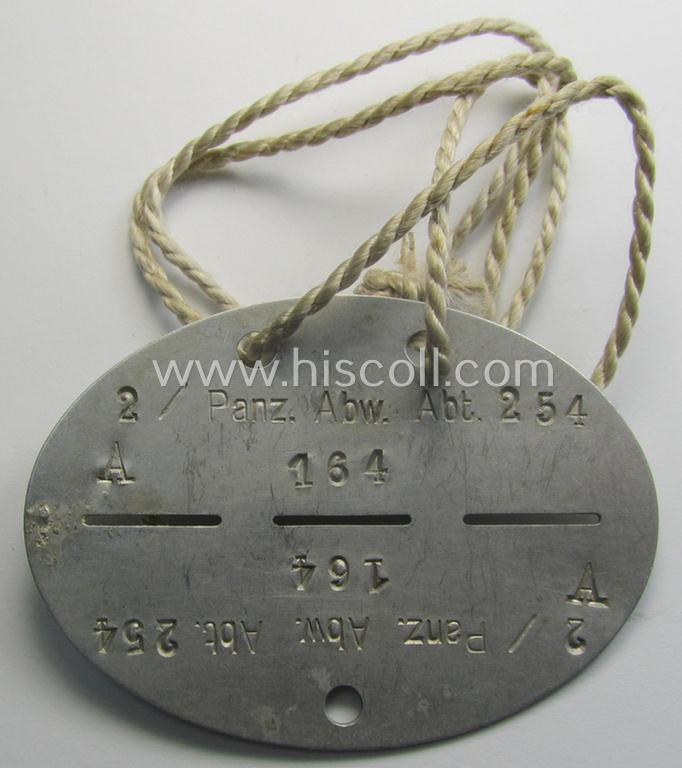 Aluminium-based, WH (Heeres) (ie. 'Pz-Abwehr'-related) ID-disc bearing the clearly stamped unit-designation that reads: '2 / Panz. Abw. Abt. 254' and that comes still mounted onto its (period-attached) cord
