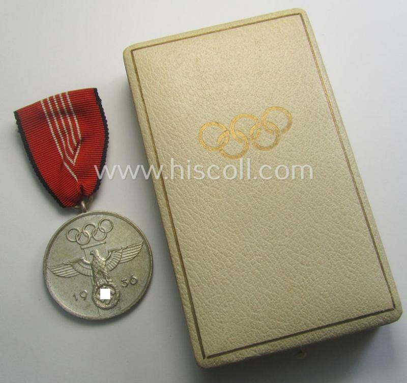 'Deutsche Olympia-Erinnerungsmedaille 1936' being a non-maker-marked example that comes mounted onto its original ribbon (ie. 'Bandabschnitt') and that comes stored in its typical, beige-white-coloured etui