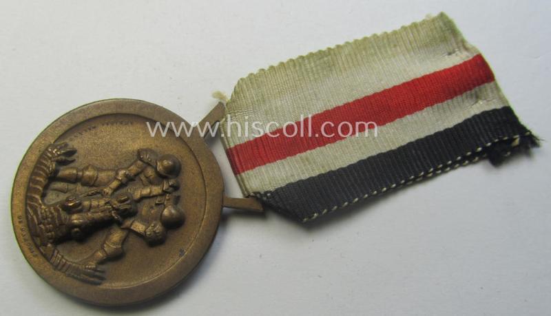 Golden-bronze-coloured- (and I deem 'Buntmetall'-based-) example of a: 'Deutsch-Italienische Feldzugsmedaille' (or: German-Italian campaign-medal) that comes mounted onto its (regular-sized) piece of original (and minimally faded!) ribbon