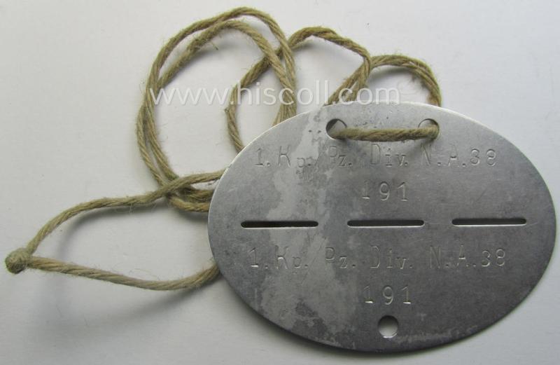 Aluminium-based, WH (Heeres) 'Panzer-Nachrichten'-related ID-disc bearing the clearly stamped unit-designation that reads: '1.Kp./Pz.Div.N.A.38' and that comes mounted onto its period cord as issued and/or worn