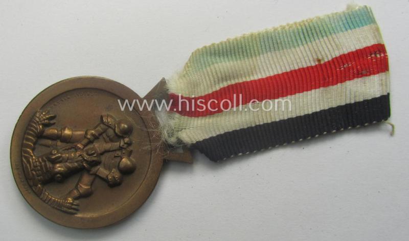 Golden-bronze-coloured- (and I deem 'Buntmetall'-based-) example of a: 'Deutsch-Italienische Feldzugsmedaille' (or: German-Italian campaign-medal) that comes mounted onto its (regular-sized) piece of original (and sun-faded!) ribbon