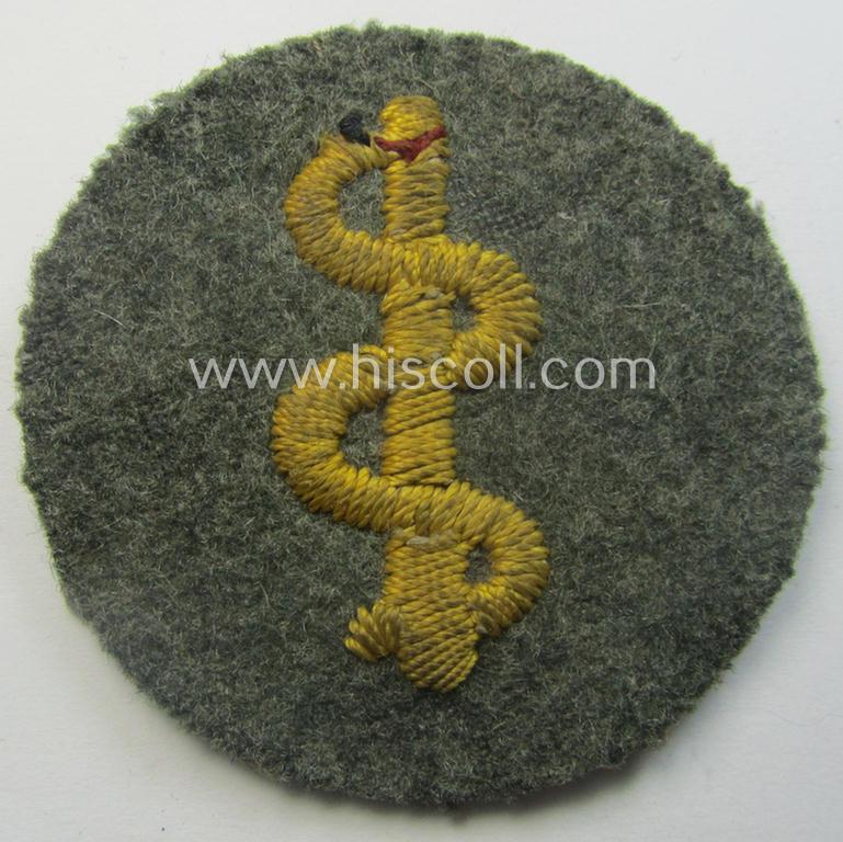 Clearly used- and/or tunic-removed WH (Heeres) so-called: trade- and/or special-career arm-insignia as was intended for a: 'Sanitäter' being a neatly hand-embroidered specimen on a field-grey-coloured background