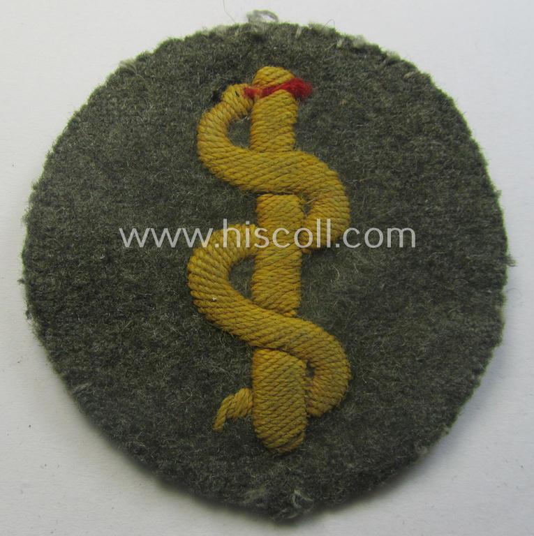 Clearly used- and/or tunic-removed WH (Heeres) so-called: trade- and/or special-career arm-insignia as was intended for a: 'Sanitäter' being a neatly hand-embroidered specimen on a field-grey-coloured background