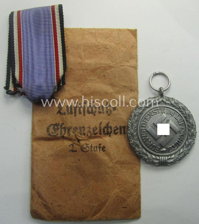'Luftschutz-Ehrenzeichen 2. Stufe' being a maker- (ie. '10'-) marked example, as executed in zinc-based metal (ie. 'Feinzink') and that comes stored in its (scarcely seen!) 'Zellstoff'-based pouch by the maker: 'Katz u. Deyhle'