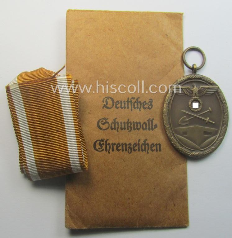 Medal-set: 'Deutsches Schutzwall Ehrenzeichen' (aka: 'Westwall'-medal) being a non-maker-marked- and/or: typical 'Buntmetall'-based specimen that comes packed in its original pouch of issue by the: 'Carl Poellath'-company