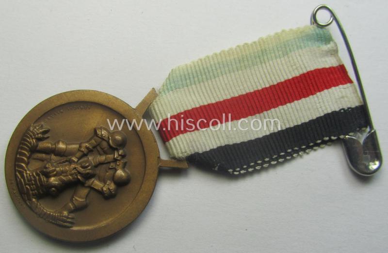 Golden-bronze-coloured- (and I deem 'Buntmetall'-based-) example of a: 'Deutsch-Italienische Feldzugsmedaille' (or: German-Italian campaign-medal) that comes mounted onto its (regular-sized) piece of original (and somewhat faded!) ribbon