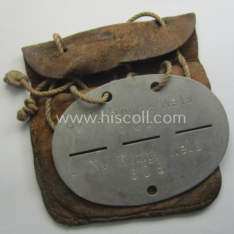 Aluminium-based, WH (Luftwaffe) ie. 'Luftnachrichten'-related ID-disc (ie. 'Erkennungsmarke') bearing the stamped unit-designation that reads: 'L.N. Komp. Wels' and that comes stored in its period (leather-based) pouch