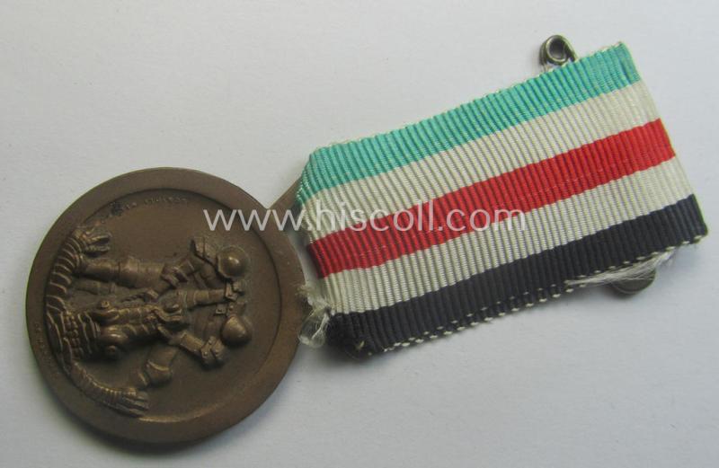 Golden-bronze-coloured- (and I deem 'Buntmetall'-based-) example of a: 'Deutsch-Italienische Feldzugsmedaille' (or: German-Italian campaign-medal) that comes mounted onto its (regular-sized) piece of original (and hardly faded!) ribbon