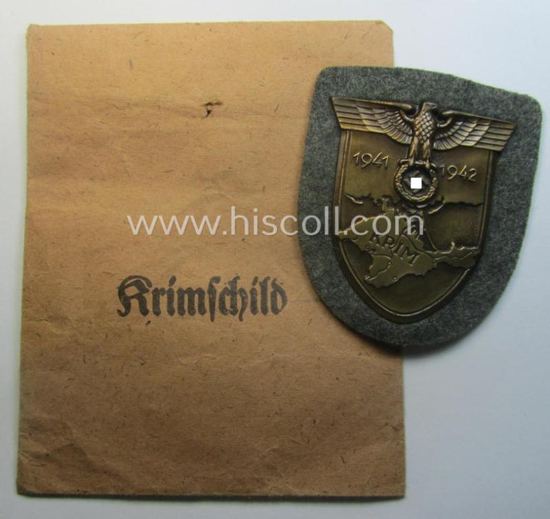 WH (Heeres ie. Waffen-SS) 'Krim'-campaign-shield (by the maker: 'Friedrich Orth') that comes stored in its period (and rarely seen!) 'Zellstoff'-based pouch and that comes in a probably issued- (albeit still 'virtually mint'-), condition