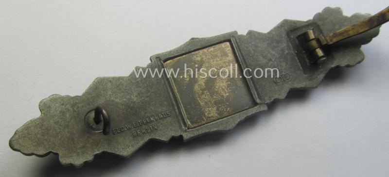 'Nahkampfspange in Bronze' (or: bronze-class close-combat clasp ie. CCC) being a maker- (ie. 'FLL'-) marked- and minimally converse-shaped so-called: '3rd pattern'-specimen as was produced by the maker- (ie. 'Hersteller') 'Friedrich Linden'