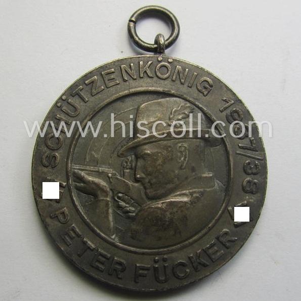 Unusually seen, frosted-silver-toned and TR-period shooting-medal showing on its front a uniformed hunter and that is entitled: 'Schützenkönig 1937/38 - Peter Fücker'