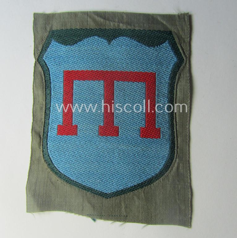 Eastern- (ie. Russian-) volunteer related armshield as executed in 'BeVo'-weave pattern depicting a red-coloured 'Tamga'-symbol as was intended for a volunteer who served within the 'Deutsche Wehrmacht' (ie. within the 'Crimean-Tartar Legion')